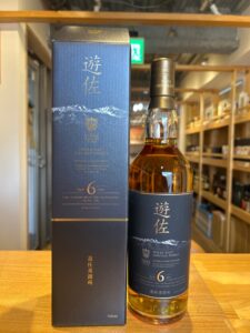 Blue box and whiskey bottle labeled Single Malt Japanese Whisky from Yuza Distillery 700ml on a wooden table in a store