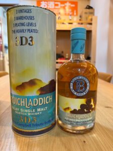 Two Bruichladdich 3D3 whisky bottles beside a cylindrical tin package on a wooden table Islay single malt scotch whisky
