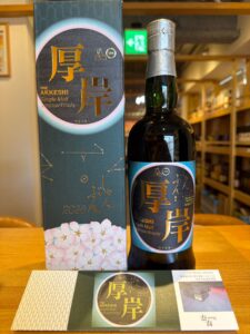 Bottle of The Akkeshi Single Malt Japanese Whisky beside its matching decorative box blue label with gold characters and hydrangea motif at the base