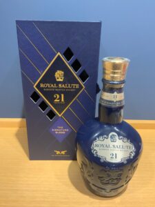 Blue Royal Salute 21 Year Old whisky bottle with ornate blue decanter next to a matching blue box on a wooden surface