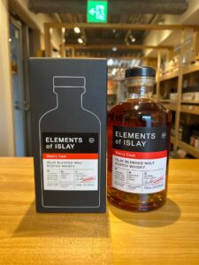 Bottle of Elements of Islay Sherry Cask whisky next to its black box on a wooden store counter