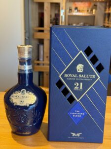 Blue ornate Royal Salute whisky bottle beside a matching blue box reading 21 Years Old and The Signature Blend on the box
