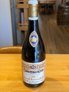 1 横浜と東京のお酒買取専門店LIQUORJOYリカージョイ Bottle of Chambertin Grand Cru wine with gold foil capsule and ornate label standing on a wooden table in a wine shop