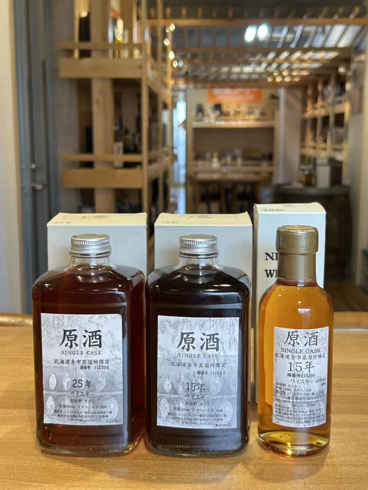 Three whiskey bottles front and center with boxed packaging behind in a shop display