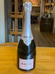 Krug Rosé champagne bottle on a wooden table in a shop foil wrapped neck and pink label visible