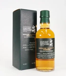 Hakushu Distillery Exclusive whiskey bottle with green cap beside its dark box, amber liquid visible in the bottle.