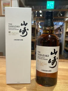 Bottle of The Yamazaki single malt Japanese whisky beside its white box on a wooden counter in a shop