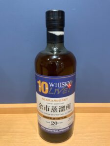 Whisky bottle labeled 10th Whisky Live with blue band Japanese text on a wooden surface
