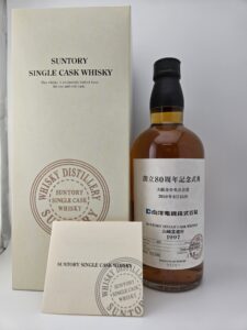 Box and bottle of Suntory Single Cask Whisky white box with SUNTORY SINGLE CASK WHISKY text and circular stamp next to a bottle with amber liquid and a black cap label mostly in Japanese with a 1997 date