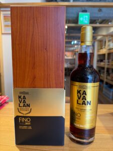 Bottle of Kavalan Fino sherry cask whisky beside its wooden box on a store counter gold label details visible