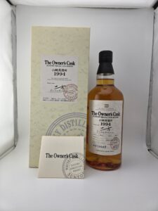 Whiskey bottle labeled The Owners Cask beside a cream gift box and accompanying booklet in a white display box