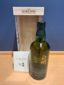 Bottle of The Hakushu single malt Japanese whisky with a wooden box and white card on a wooden surface
