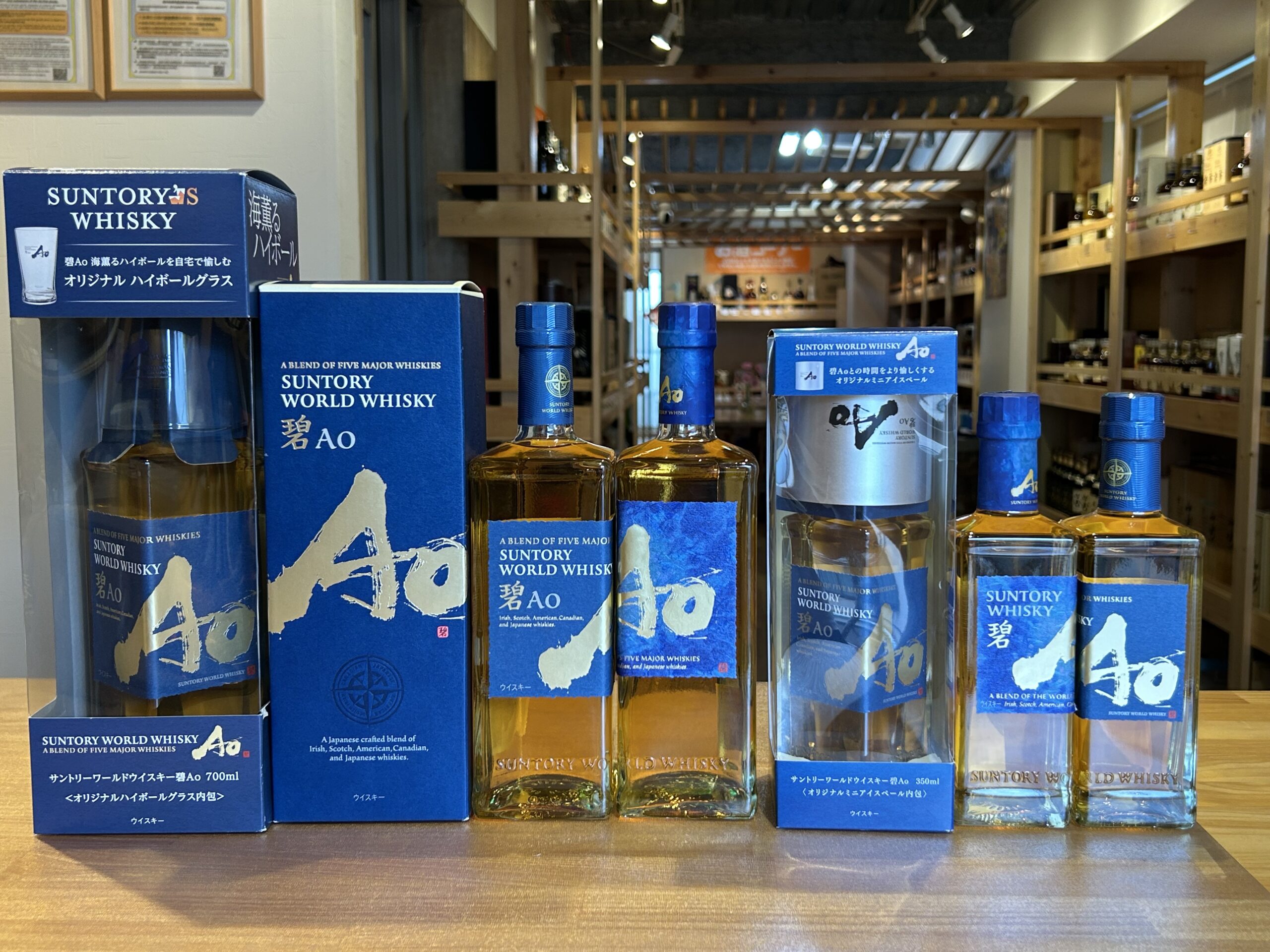 Blue boxes and bottles of Suntory World Whisky on a display shelf in a liquor store