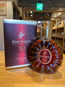 Rémy Martin XO cognac bottle with its purple box on a wooden counter in a shop setting