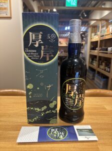 Whisky bottle and matching decorative blue box labeled The Akkeshi placed on a wooden table in a shop window display