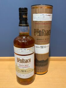 SCtr4CPM7lq307xdAY00vfwVufDUjUGuYYZlKIOg 横浜と東京のお酒買取専門店LIQUORJOYリカージョイ Close up of a BenRiach single malt whisky bottle in front with a gold taped cylindrical display tube labeled BenRiach in the background on a wooden surface