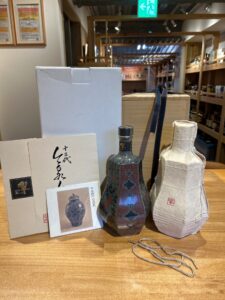 Display of decorative ceramic vases in Japanese style packaging on a wooden counter with boxes and a rope nearby
