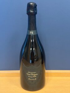Dom Pérignon champagne bottle with foil wrapped cork against a blue background vintage 2008 label visible on the front