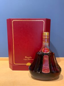 Paradis Cognac bottle with red presentation box and blue wall in the background