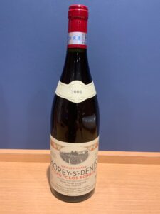 Tall red wine bottle with red foil capsule vintage 2004 Morey St Denis label visible at the neck and body
