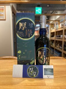 Bottle of The Akkeshi Single Blended Japanese Whisky Peated beside its blue box on a wooden counter in a shop.