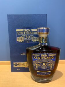 Blue box and bottle of Ron Centenario 30th anniversary rum with gold lettering and detailing
