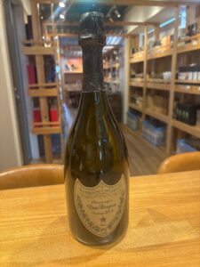 1 お酒買取専門店LIQUORJOYリカージョイ Champagne bottle with foil wrapped neck on a wooden counter store shelves in background