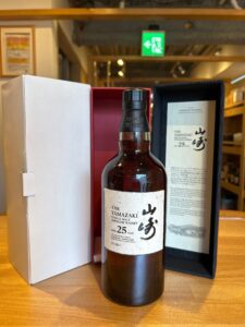 Bottle of Yamazaki 25 year single malt whisky in its black presentation box with white label visible on the bottle cap area and surrounding packaging edge