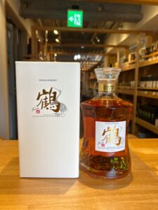 NIKKA WHISKY bottle with white box beside it on a wooden counter in a liquor store