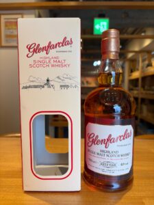 Glenfarclas Highland Single Malt Scotch Whisky bottle next to its white box on a table, copper cap visible in foreground.