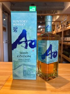 Bottle of Suntory Whisky Irish Edition next to its blue green box on a wooden table