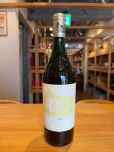 T59h0wSgzacA8NTbTrctdV28KtDuVE5PsScJ4hGw お酒買取専門店LIQUORJOYリカージョイ Wine bottle on a wooden table with a cream label featuring a detailed château illustration and Chateau Haut Brion 1999 text visible in a store setting