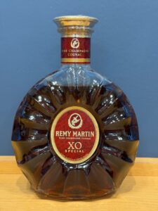 TgqhTxmBzKP8defvcwz57BCLkedNIUm0KM5V9usw お酒買取専門店LIQUORJOYリカージョイ Close up of a Remy Martin XO Special cognac bottle with a red label and gold cap against a blue background
