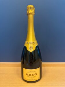 Champagne bottle with gold foil and Krug Grande Cuvée label against a blue background