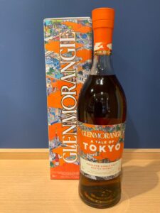 aveycFHxdfSWItcr4z4265gd0HuqQ5WxprXuQ66f お酒買取専門店LIQUORJOYリカージョイ Bottle of Glenmorangie Tokyo limited edition whisky with bright orange cap beside a colorful Tokyo themed box on a wooden surface against a blue wall