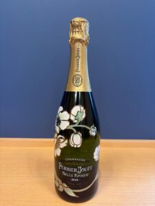 Perrier Jouët Belle Époque champagne bottle with gold foil and floral artwork on a dark glass bottle standing on a wooden surface