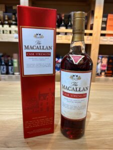 1 お酒買取専門店LIQUORJOYリカージョイ Bottle of The Macallan Cask Strength Highland Single Malt Scotch Whisky next to its red boxed packaging on a wooden surface label visible saying The Macallan Cask Strength