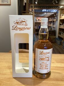 Bottle of Longrow single malt Scotch Whisky beside its white packaging box with red Longrow logo in a store setting