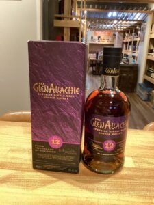 1 お酒買取専門店LIQUORJOYリカージョイ Bottle of The GlenAllachie 12 year old Speyside single malt whisky beside its purple box on a wooden table in a shop setting