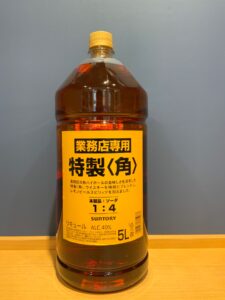 2ysmftIuR2Tb9uGRfiE8Wg7q2e7V4TGo7t1KbYQp お酒買取専門店LIQUORJOYリカージョイ Five liter plastic bottle of orange brown liquid with a yellow cap and bright orange label containing Japanese text and the Suntory logo sitting on a wooden surface