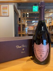 G9uJrFUKceAWnMePaN6EJ5QkzV5BfAvKa2g5uvor お酒買取専門店LIQUORJOYリカージョイ Bottle of Dom Pérignon Rosé champagne with pink label next to a dark purple box on a wooden surface in a store display