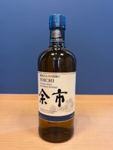 SPCPvJx2LOqQlM2oePMBrftFr9hSzYS9fTOKDEb8 お酒買取専門店LIQUORJOYリカージョイ Bottle of Nikka Whisky Yoichi single malt Japanese whisky on a wooden table with a blue background blue cap visible