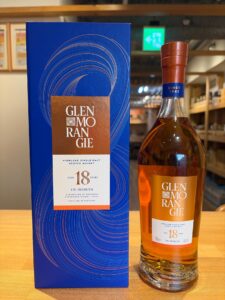 Glenmorangie 18 year old whisky bottle next to its blue decorative box on a wooden surface in a store