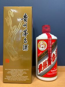 Gold packaging box with Chinese characters beside a white bottle of Moutai and a red ribbon
