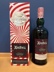 1 お酒買取専門店LIQUORJOYリカージョイ Ardbeg Islay single malt whisky bottle beside a red and white spiral striped box on a wooden surface