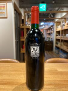 1 お酒買取専門店LIQUORJOYリカージョイ Wine bottle centered on a wooden table in a shop label reads Screaming Eagle with red foil top
