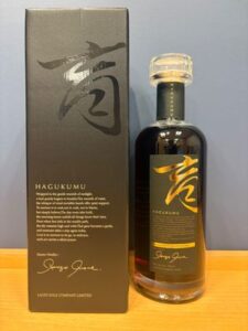 Bottle of liquor beside its black box both showing a bold gold calligraphic character cork sealed bottle on a wooden surface