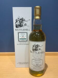 10Ke2MYDhQlsoiJC0tjbWzJvUoAfVafWX6tQXOIn お酒買取専門店LIQUORJOYリカージョイ Bottle of Battlehill 12 year old Scotch whisky beside its striped box on a wooden surface with a drawn historical scene on the label and box