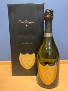 Dom Pérignon champagne bottle beside a black box on a wooden surface label reads Vintage 1990