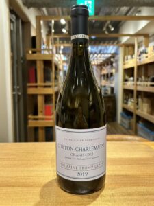 1 お酒買取専門店LIQUORJOYリカージョイ Wine bottle centered on a wooden table in a wine shop label reads Corton Charlemagne Grand Cru 2019 Domaine Bruno Clair